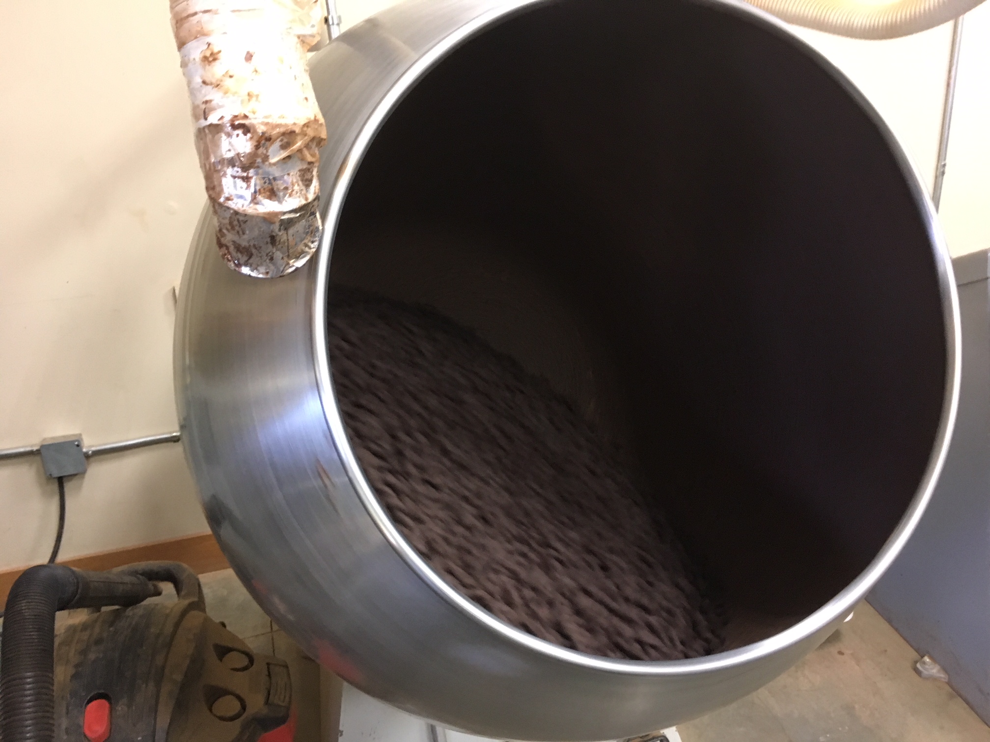 A chocolate panning machine burnishing chocolate covered almonds to a perfect shape